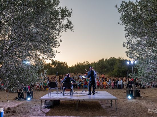 Ein Cellist und ein Violinist musizieren auf einer Bühne umgeben von Bäumen in einem Olivenhain beim  9. Molyvos International Music Festival auf der Insel Lesbos.