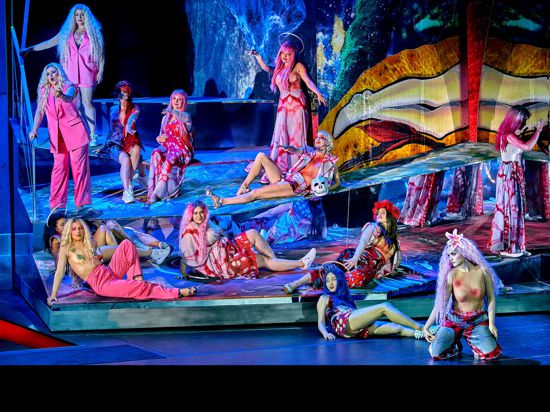 Szene aus der Oper „Parsifal“ bei den Bayreuther Festspielen mit Blumenmädchen auf der sehr bunten Bühne.