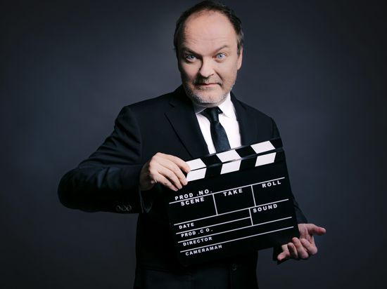Porträt des Schauspielers und Sprechers Jens Wawrczeck mit einer Filmklappe.