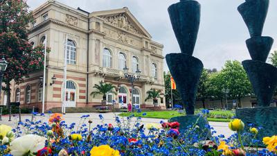 Vor dem Theater in Baden-Baden blühen Blumen in einem Beet. 