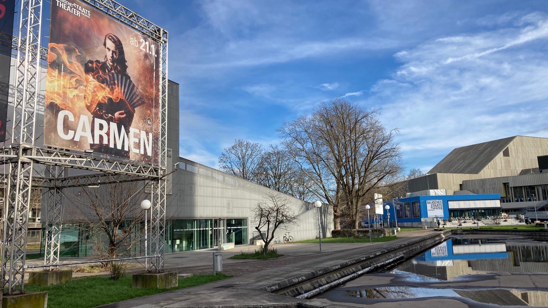 Vor dem Badischen Staatstheater in Karlsruhe deutet ein großes Werbebanner auf die Premiere von „Carmen“ hin. 