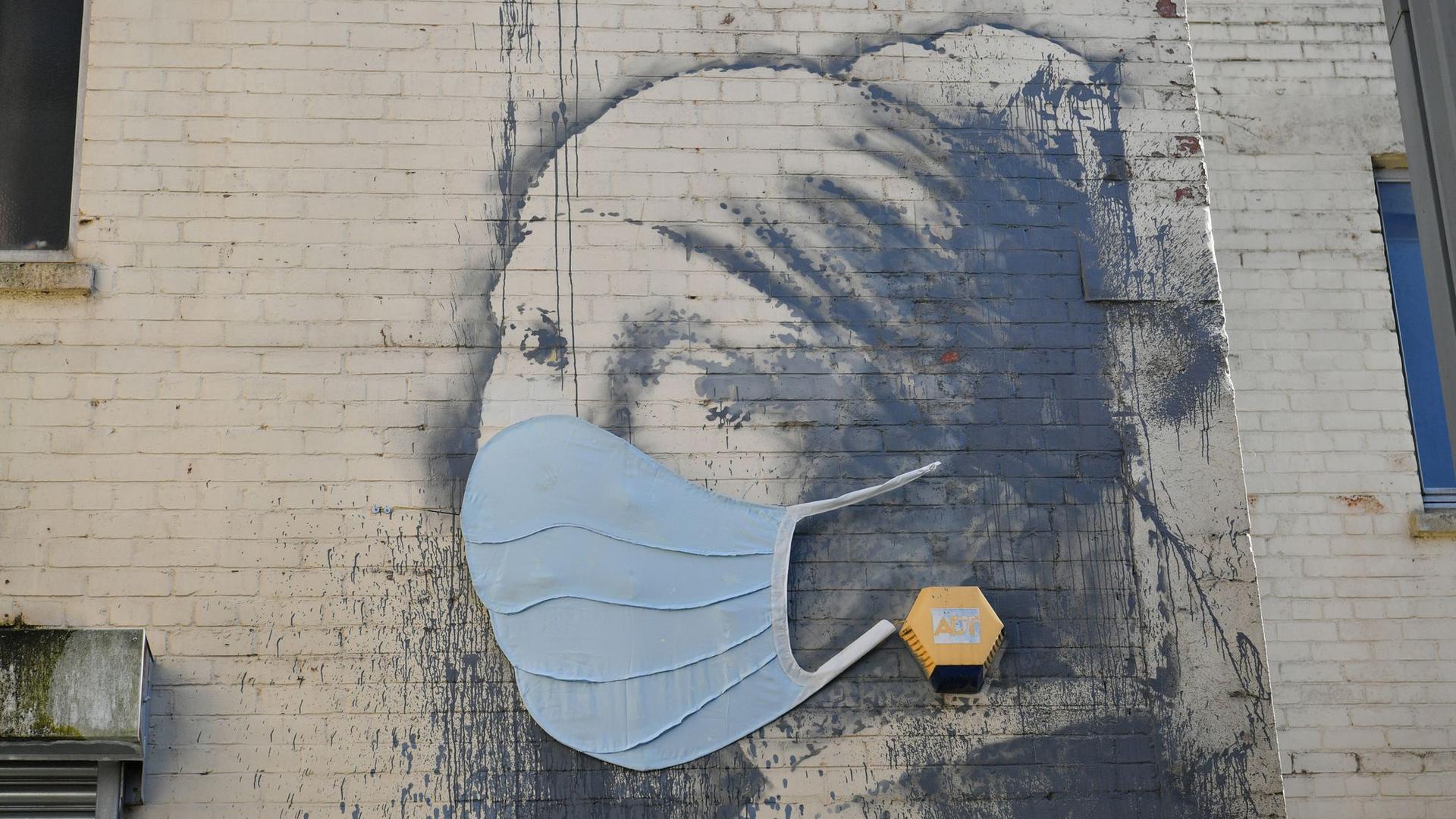 Das Wandgemälde „Das Mädchen mit dem Perlenohrring“ in Bristol, das von Banksy stammen soll, hat als Reaktion auf die Coronavirus-Pandemie eine Gesichtsmaske bekommen.