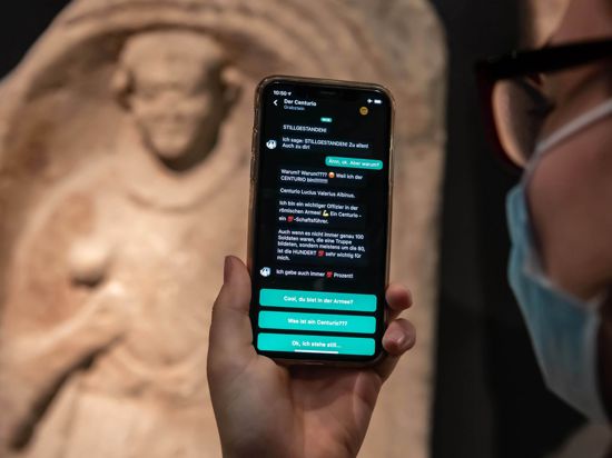 Im Badischen Landesmuseum wird vor einem Grabstein eines Centurio aus dem 1. Jahrhundert nach Christus auf einem Smartphone eine App gezeigt, mit der Museumsbesucher Kontakt zu Ausstellungsobjekten aufbauen können.