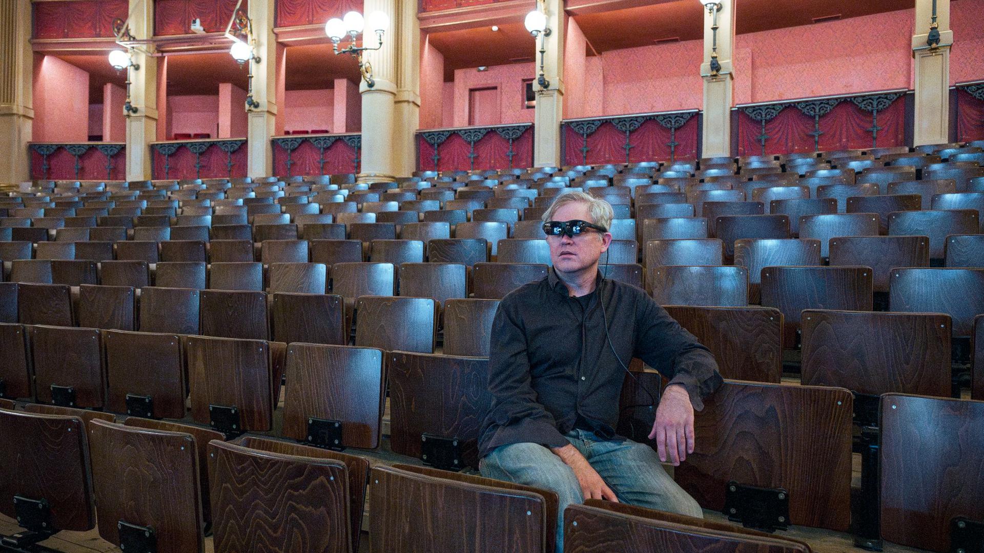 Jay Scheib, Regisseur der Neuproduktion des „Parsifal“, sitzt mit einer Augmented Reality (AR) Brille im Zuschauerraum des Festspielhauses.