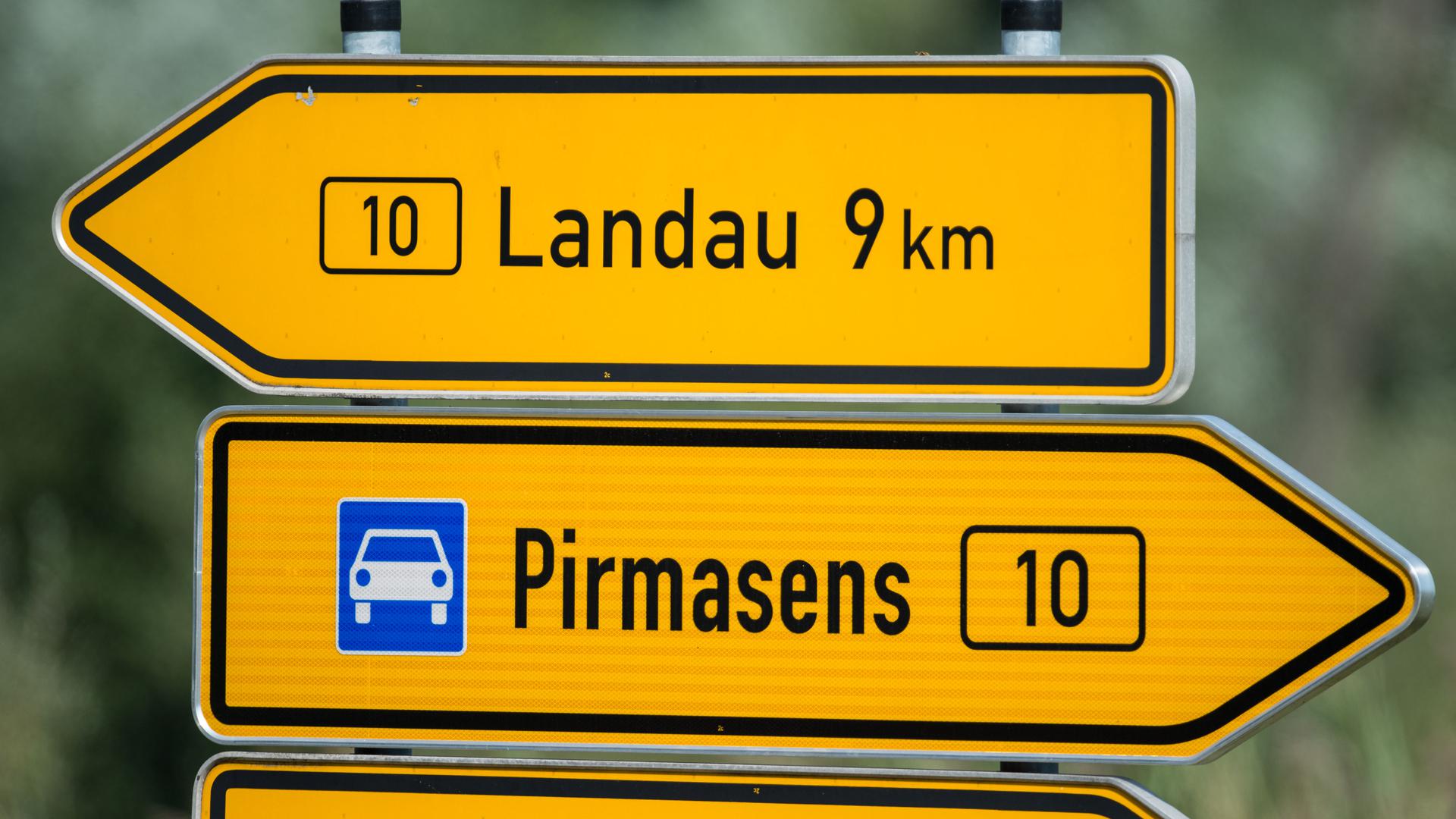 Zwei Straßenschilder mit der Aufschrift „Landau“ und „Pirmasens“ stehen an der Bundesstraße 10. 
