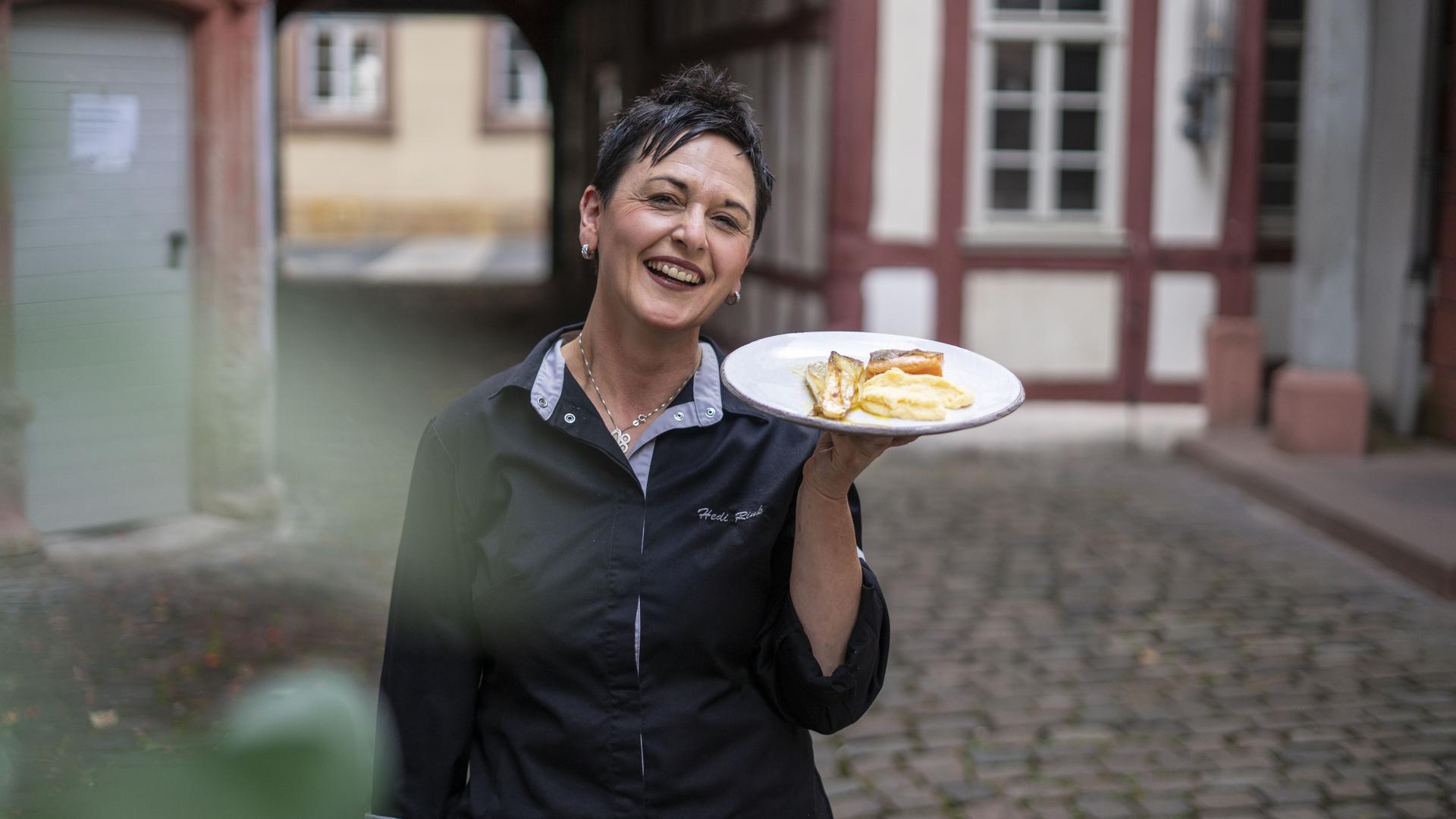 Hedi Rink im Hof ihres Restaurants mit einem Teller in der Hand.
