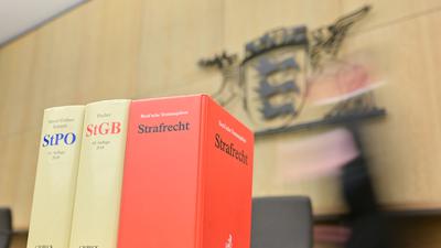 Ein Richter geht in einem Sitzungssaal des Landgerichts Mannheim an der Richterbank zu seinem Sitzplatz. Im Vordergrund stehen Bücher mit der Aufschrift „StPO“, „StGB“ und „Strafrecht“. 