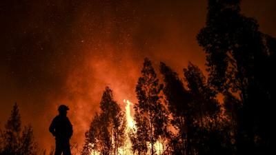 Ein Feuerwehrmann beobachtet einen brennenden Wald in Portugal.
