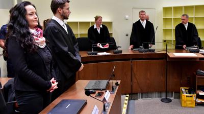 Die Angeklagte Beate Zschäpe steht neben ihrem Anwalt Mathias Grasel während der Vorsitzende Richter Manfred Götzl (2.v.r.)und die Vertreter des Staatsschutzsenats Gabriele Feistkorn (l), Peter Lang (2.v.l.)und Konstantin Kuchenbauer (2.v.r) den Gerichtssaal betreten. Am 11. Juli 2018 wurde vor dem Oberlandesgericht in München ein Urteil im NSU-Prozess um Zschäpe gesprochen. Die als Nationalsozialistischer Untergrund (NSU) bezeichnete Terrorgruppe hatte zwischen den Jahren 2000 und 2007 zehn Menschen in Deutschland ermordet. (zu dpa «Zum Jahrestag Urteil im NSU-Prozess gegen Beate Zschäpe und Co. am 11. Juli») +++ dpa-Bildfunk +++