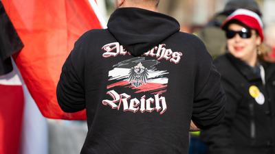 Ein Mann trägt einen Pullover mit dem Aufdruck „"Deutsches Reich" bei einer Demonstration von Reichsbürgern. Sogenannte Reichsbürger und andere Demokratiegegner demonstrieren in der Nähe des Neuen Palais. 