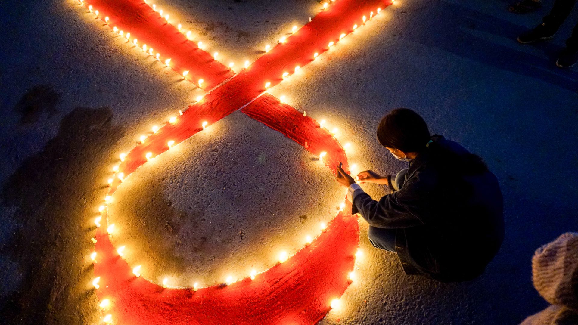 Eine Frau stellt auf einer Veranstaltung im Vorfeld des Welt-Aids-Tags Kerzen auf, die eine rote Schleife formen – ein weltweit anerkanntes Symbol für die Solidarität mit HIV-Infizierten. 