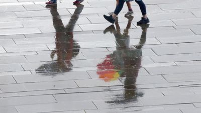 Menschen laufen bei Temperaturen um 15 Grad Celsius mit Regenschirmen durch das Regierungsviertel. Nach Angaben der Meteorologen wird auch in den kommenden Tagen mit schauerartigen Regenfällen zu rechnen sein. +++ dpa-Bildfunk +++