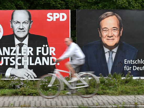 Ein Radfahrer fährt an großen Wahlplakaten mit den Spitzenkandidaten Olaf Scholz (SPD, l) und Armin Laschet (CDU) vorbei.