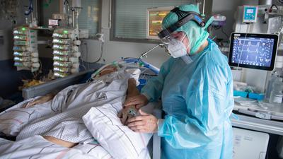 Eine Intensiv-Pflegerin versorgt einen schwer an Corona erkrankten Patienten auf der Intensivstation des Klinikums in Fulda. Viele Patienten mit schweren Verläufen liegen mehrere Wochen auf der Intensivstation, rund die Hälfte der künstlich beatmeten Patienten stirbt. +++ dpa-Bildfunk +++