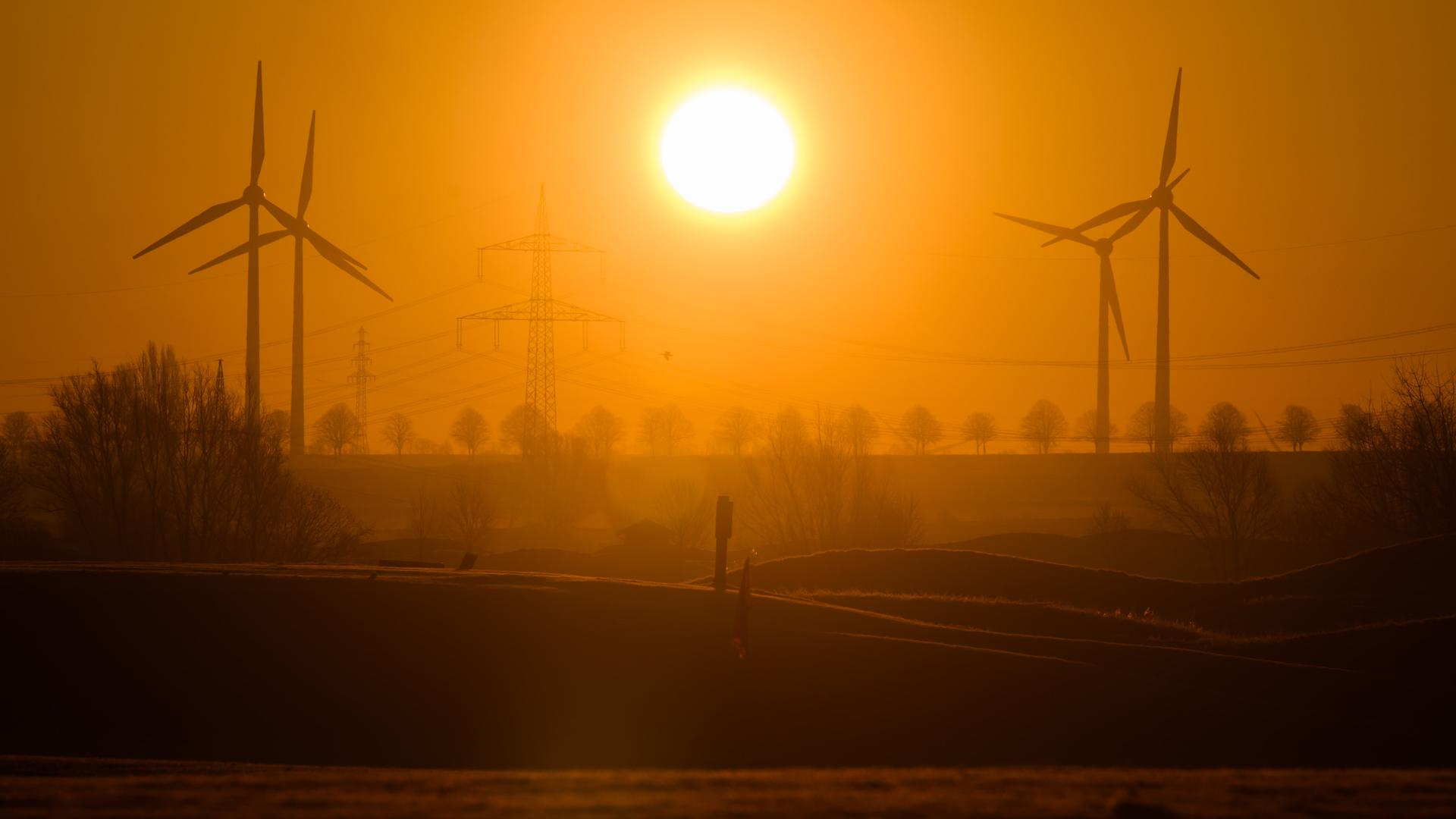 Die Sonne geht zwischen Windrädern und einer Hochspannungsleitung in der Region Hannover auf. Die EU-Kommission plant einen «Pakt für erneuerbare Energien», um die Gasnutzung zu reduzieren und den Ausbau von Solarenergie, Wind- und Wasserkraft anzukurbeln. +++ dpa-Bildfunk +++