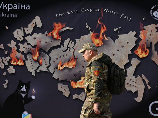 Ein ukrainischer Soldat geht an einem Wandbild mit der Abbildung Russlands und der Aufschrift „Das Imperium muss fallen“ vorbei