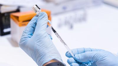 Ein Mitarbeiter eines mobilen Impfteams zieht eine Spritze mit dem Corona-Impfstoff auf. 