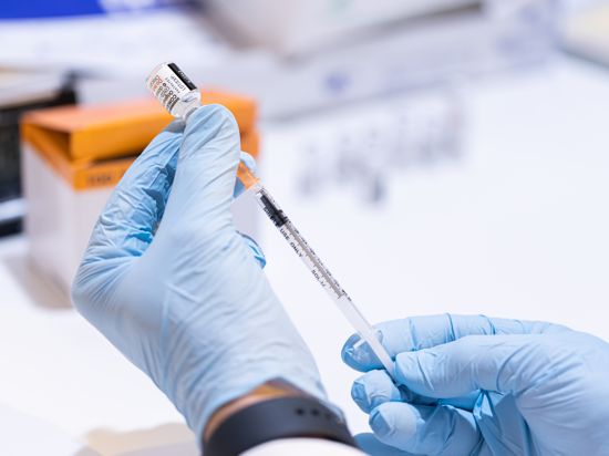 Ein Mitarbeiter eines mobilen Impfteams zieht eine Spritze mit dem Corona-Impfstoff auf. 