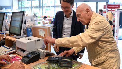 Peter Jordan, 86, steckt seine Gesundheitskarte in ein Kartenlesegerät, um in einer Apotheke Medikamente zu kaufen, daneben steht Bundesgesundheitsminister Karl Lauterbach (l, SPD) der das Verfahren zur Ausstellung eines elektronischen Rezepts vorstellt. 
