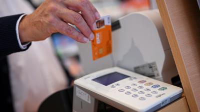 Eine Person legt die Gesundheitskarte eines Patienten in ein Kartenlesegerät in einer Apotheke