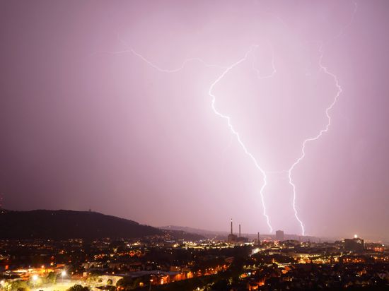 Zwei Blitze entladen sich während eines Gewitters hinter dem Gaskessel in Stuttgart. 