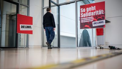 Ein Mitarbeiter des Bundestags geht zum Sitzungssaal der Fraktion von Die Linke auf der Fraktionsebene im Bundestag neben einem Plakat mit der Aufschrift «So geht Solidarität:» . 