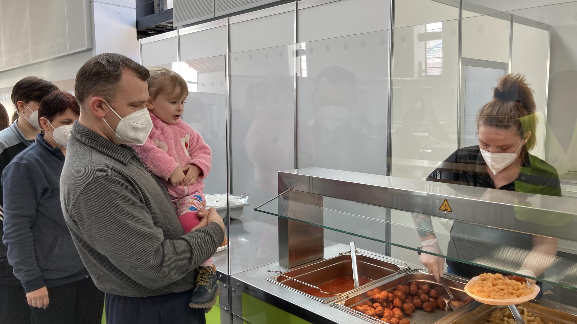 Ein warmes Essen in der Notunterkunft: Ukrainische Familien holen sich in der provisorischen Kantine in der Messe Karlsruhe ihren Teller voll Nudeln und Fleischbällchen ab. 