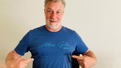 Sänger Marc Marshall zeigt auf die Aufschrift „Alles Gute“ auf seinem blauen T-Shirt. 