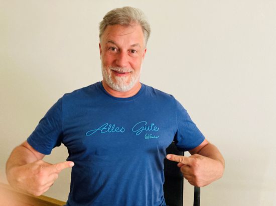 Sänger Marc Marshall zeigt auf die Aufschrift „Alles Gute“ auf seinem blauen T-Shirt. 