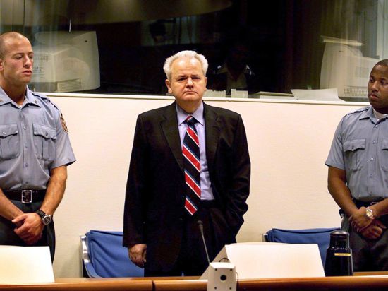 ARCHIV - Der frühere jugoslawische Präsident Slobodan Milosevic (M) steht zwischen zwei Justizbeamten bei seiner dritten Vorführung vor dem UN-Kriegsverbrechertribunal in Den Haag (Archivfoto vom 29.10.2001). Der 64-Jährige starb während des Prozesses in der Zelle des UN-Kriegsverbrechertribunals.  dpa   (zu dpa-Hintergrund: "Terroristen und Völkermörder jahrelang gejagd")  +++(c) dpa - Bildfunk+++