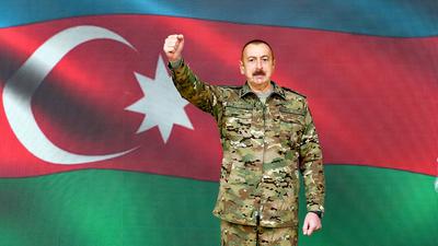 Ilham Aliyev, Präsident von Aserbaidschan, steht in Baku vor einer Projektion der Nationalflagge.