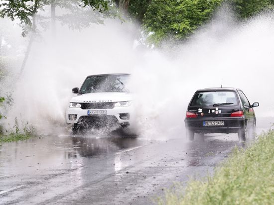 Autos fahren durch die überflutete Erkrather Landstraße im Stadtteil Hubbelrath. Starkregen hat Straßen in Düsseldorf unter Wasser gesetzt. +++ dpa-Bildfunk +++