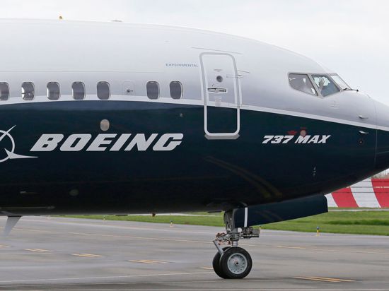 Ein Pilot winkt aus der Pilotenkabine eines Flugzeuges vom Typ Boeing 737 MAX auf dem Flughafen.