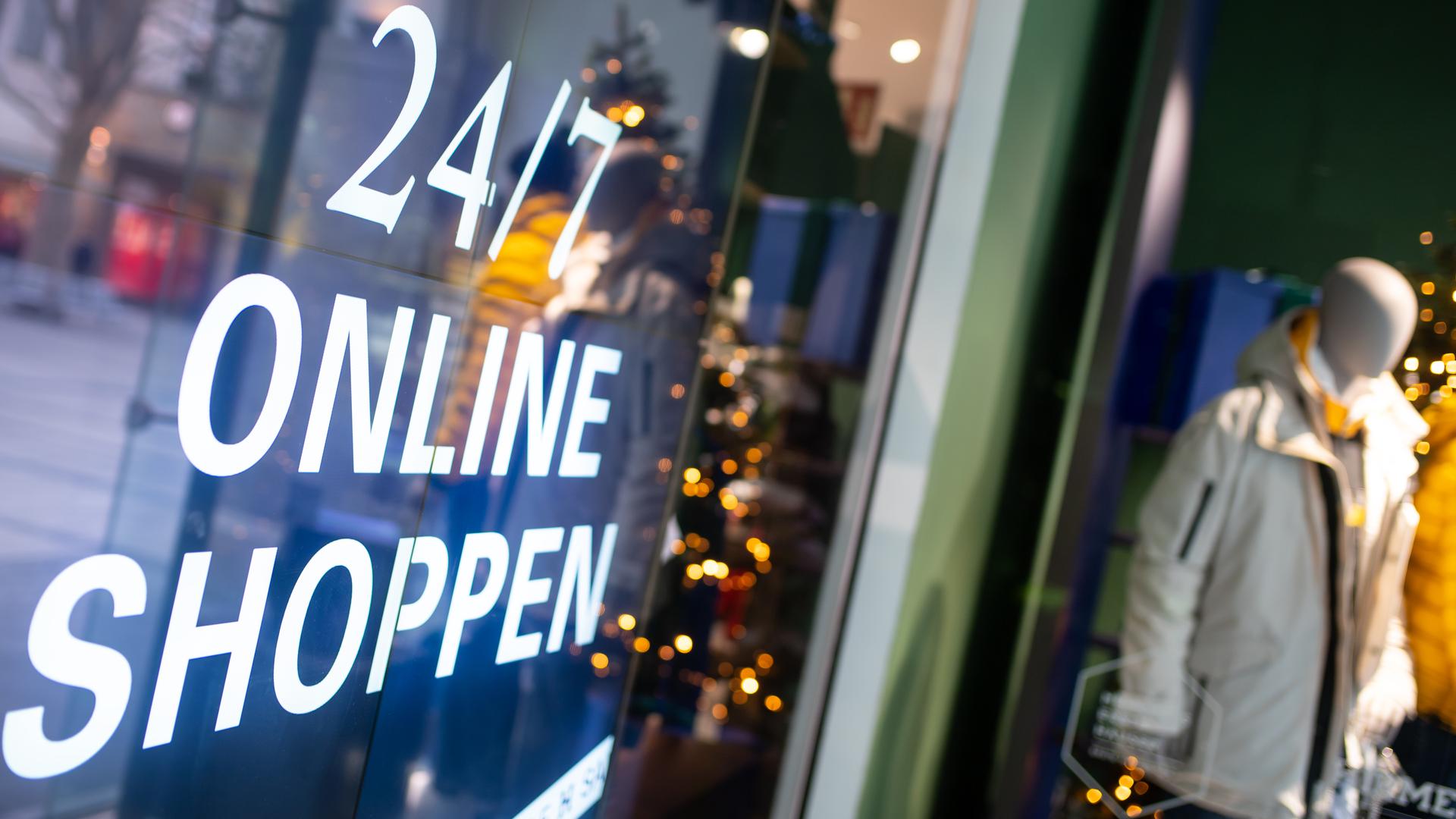 Ein Bildschirm mit der Aufschrift "24/7 Online Shoppen" ist im Schaufenster von einem geschlossenen Geschäft in der Innenstadt zu sehen. 