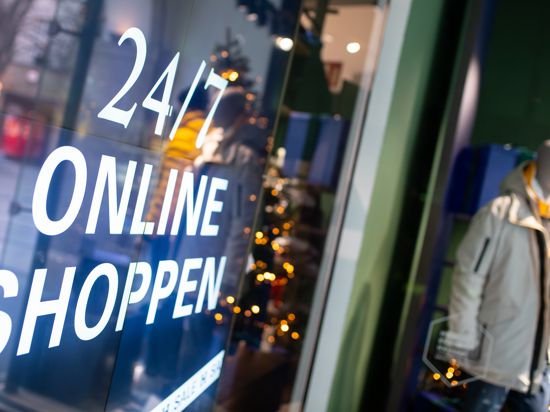 Ein Bildschirm mit der Aufschrift "24/7 Online Shoppen" ist im Schaufenster von einem geschlossenen Geschäft in der Innenstadt zu sehen. 