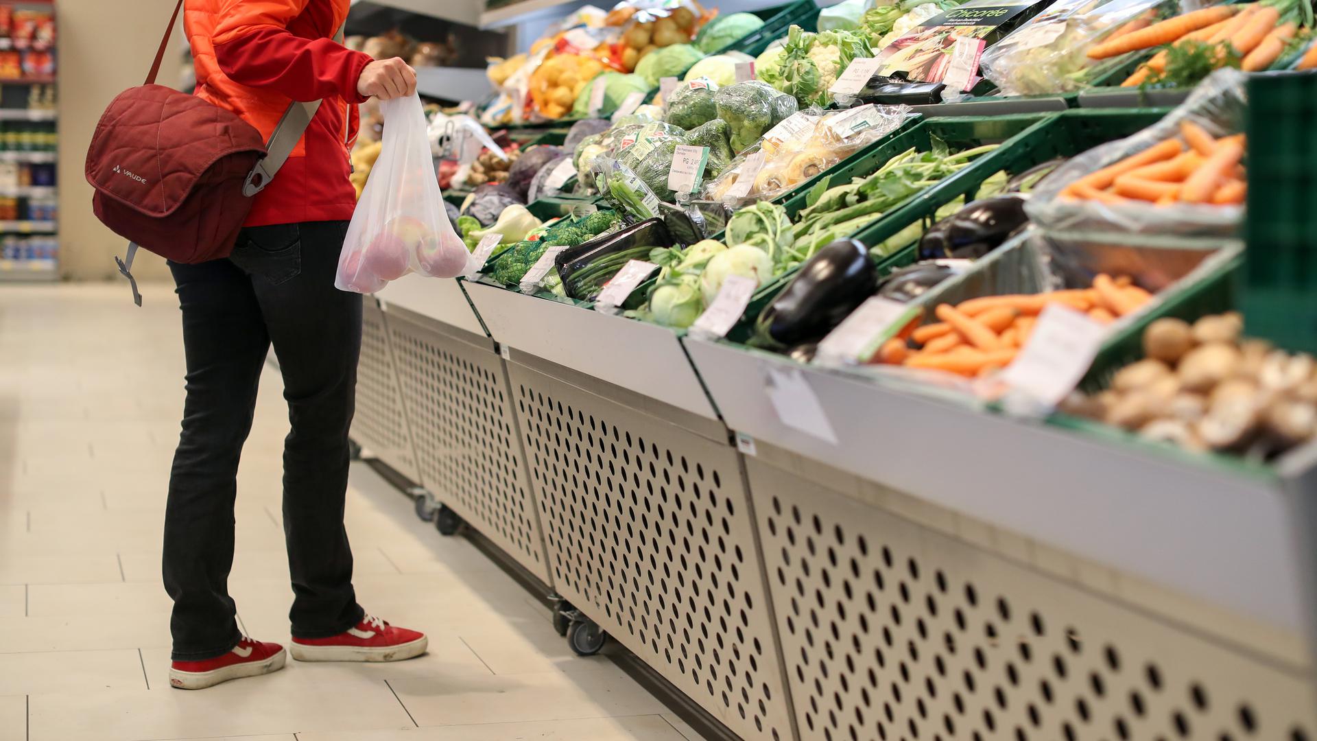 Eine Kundin steht in der Obst- und Gemüseabteilung in einem Supermarkt. 
