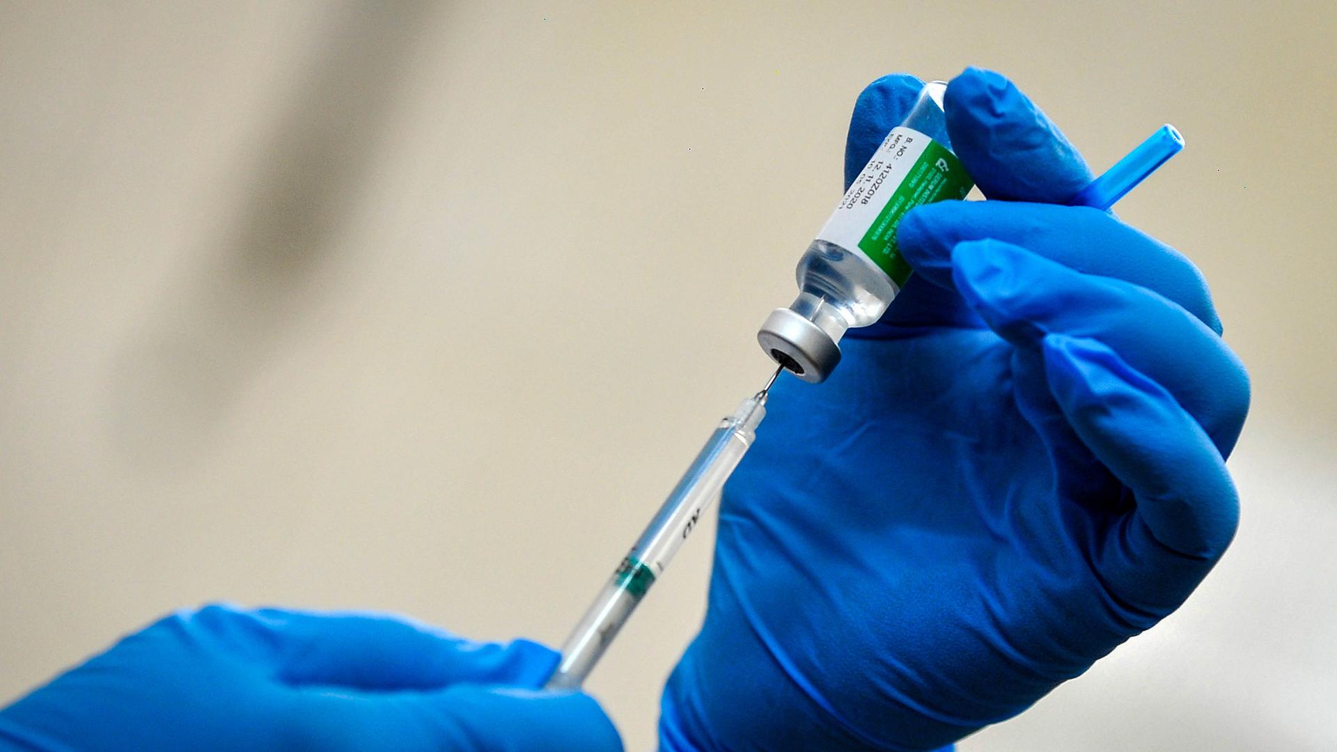 Ein Mitarbeiter des Gesundheitswesen zieht eine Spritze mit dem Corona-Impfstoff von AstraZeneca auf. 