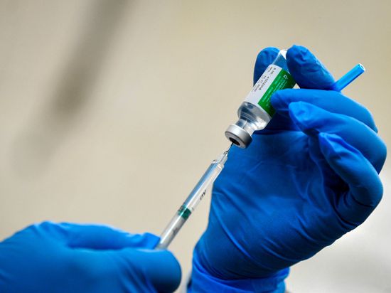 Ein Mitarbeiter des Gesundheitswesen zieht eine Spritze mit dem Corona-Impfstoff von AstraZeneca auf. 