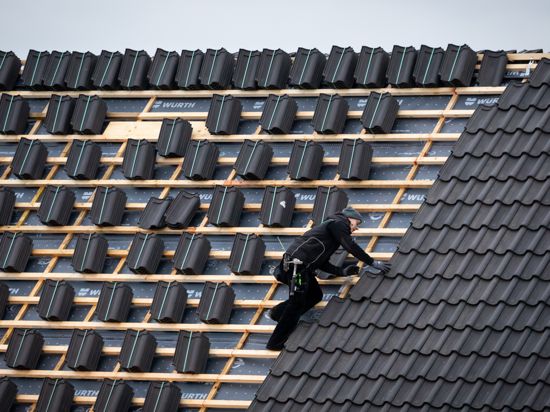Ein Dachdeckermeister setzt eine Dachpfanne auf der Dachfläche eines Schulgebäudes. (zu dpa «Handwerk mit mehr Umsatz und weniger Beschäftigten») +++ dpa-Bildfunk +++