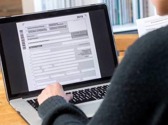 Ein Mann sitzt an einem Laptop und schaut auf seine digitale Einkommensteuererklärung.