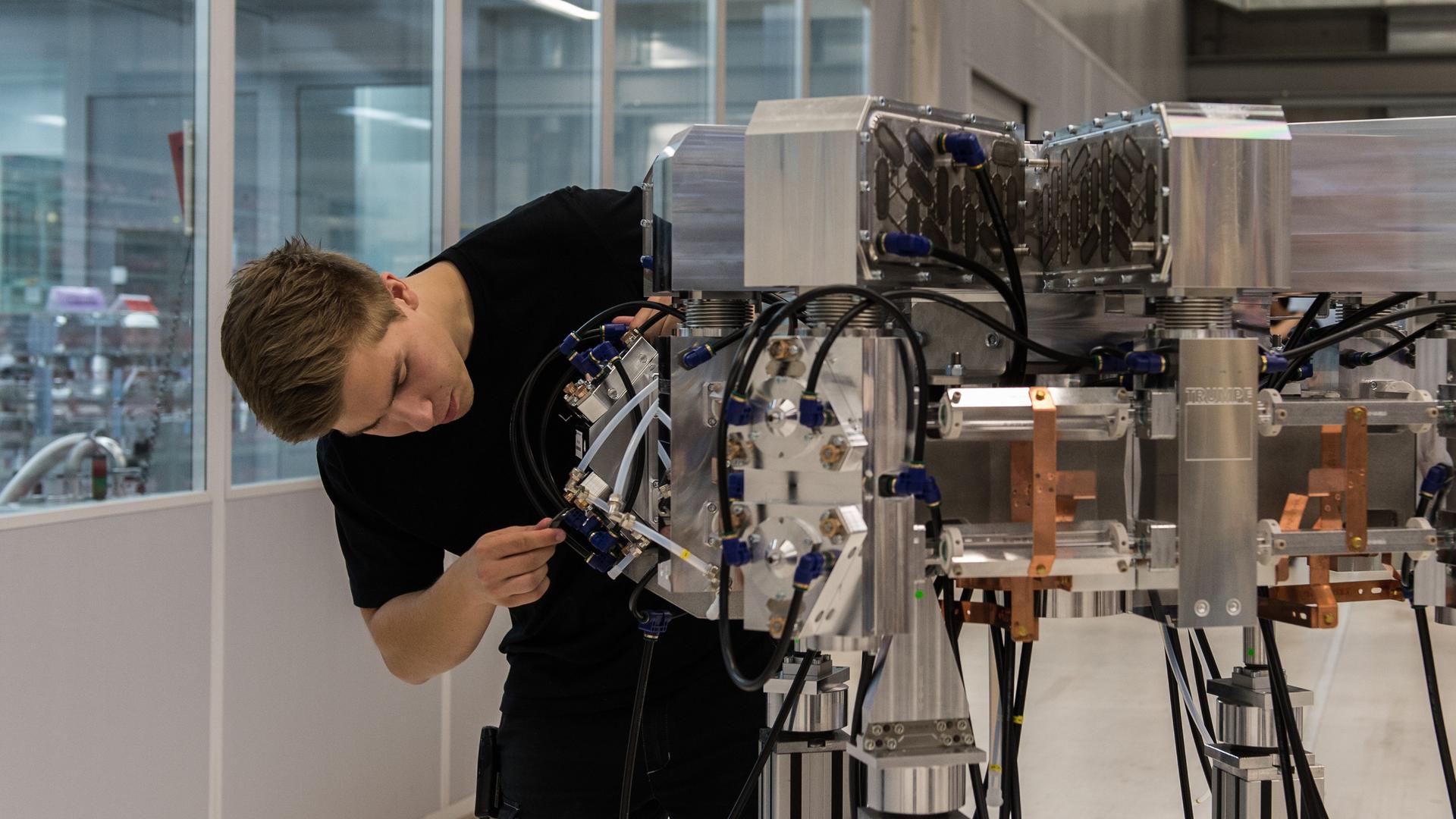 Ein Produktionstechnologe in Ausbildung arbeitet an einem Laserresonator.