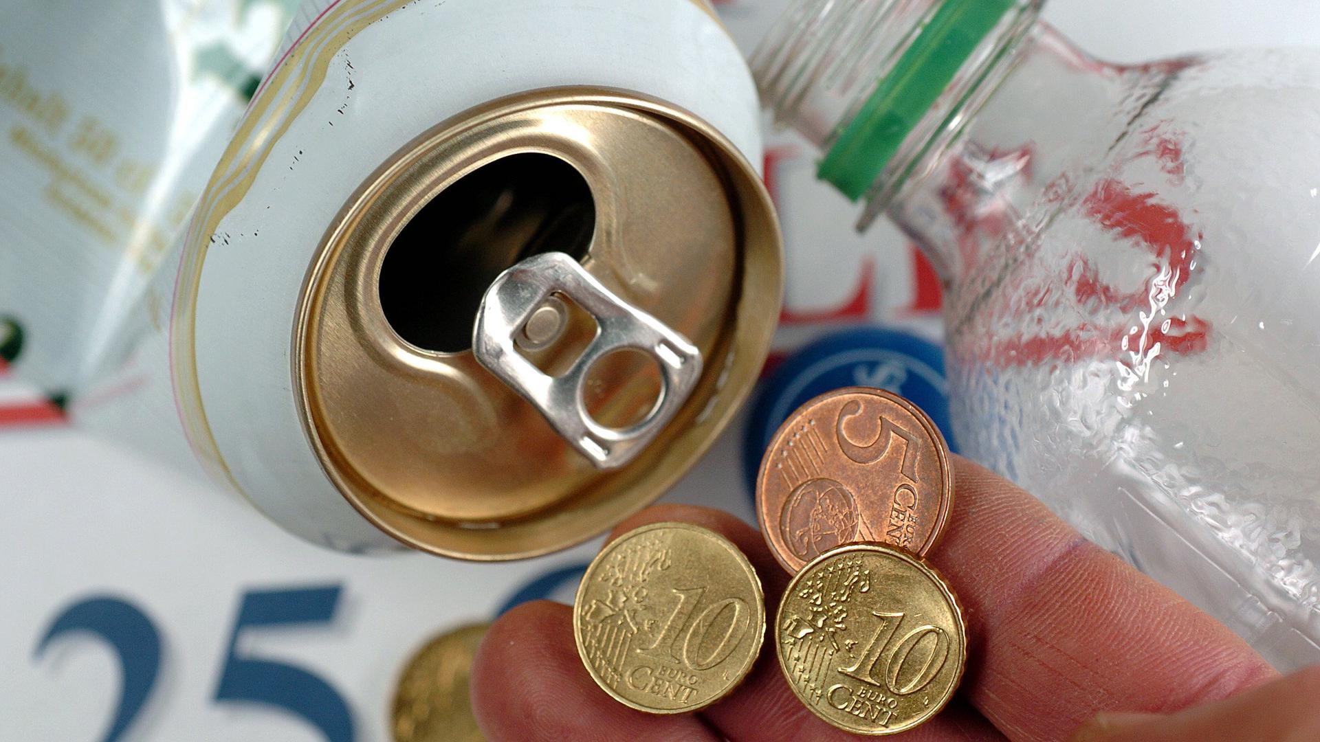 Eine Hand hält in Schwerin die Pfandgebühr von 25 Cent über einer leeren Getränkedose 