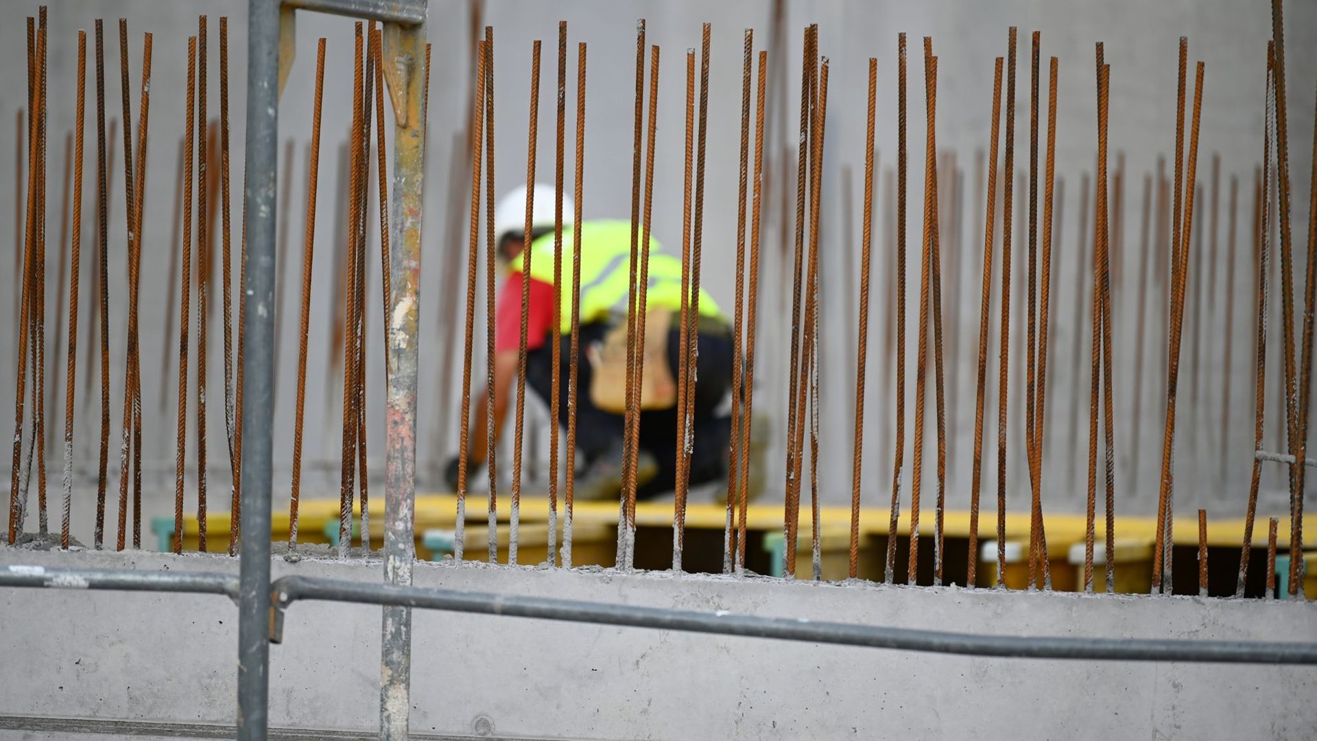 Ein Handwerker arbeitet auf einer Baustelle an Betonstahlträgern.