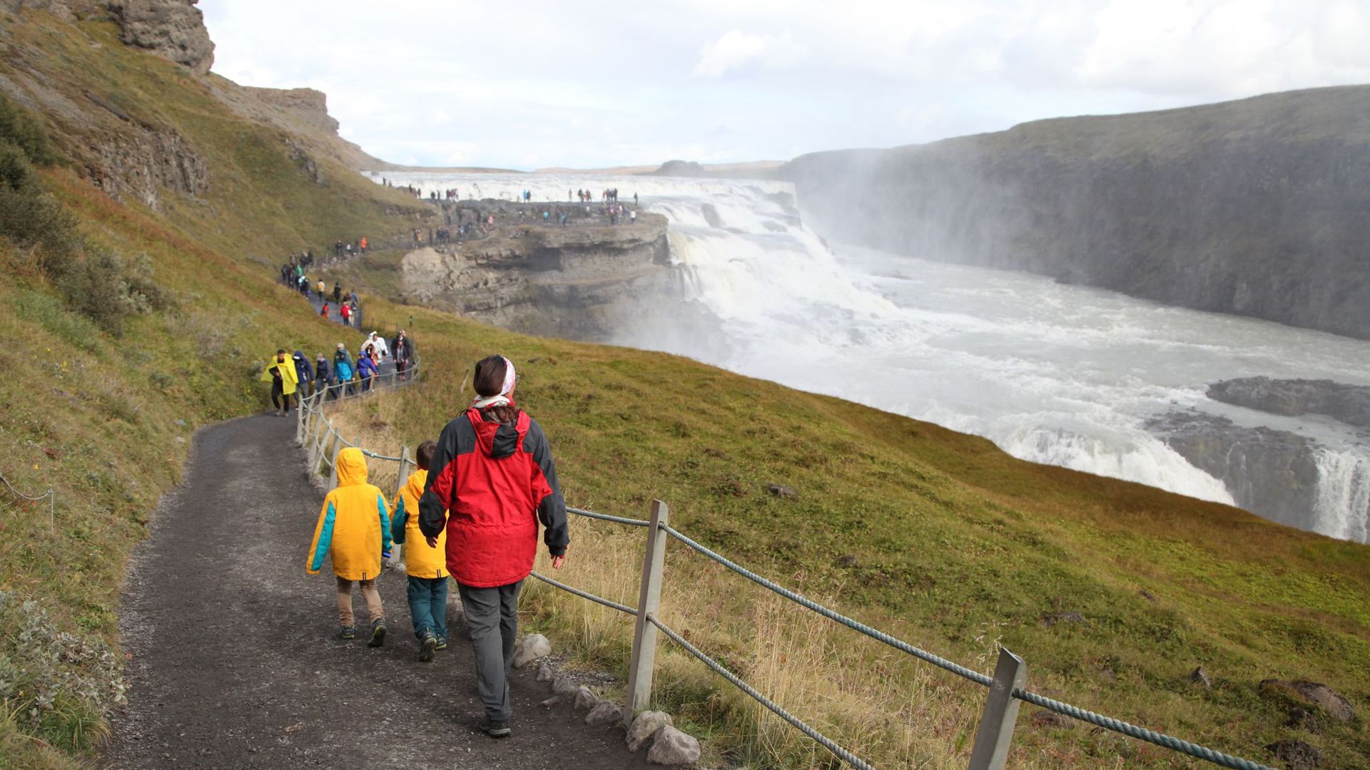 Touristen wandern zum Wasserfall Gullfoss.