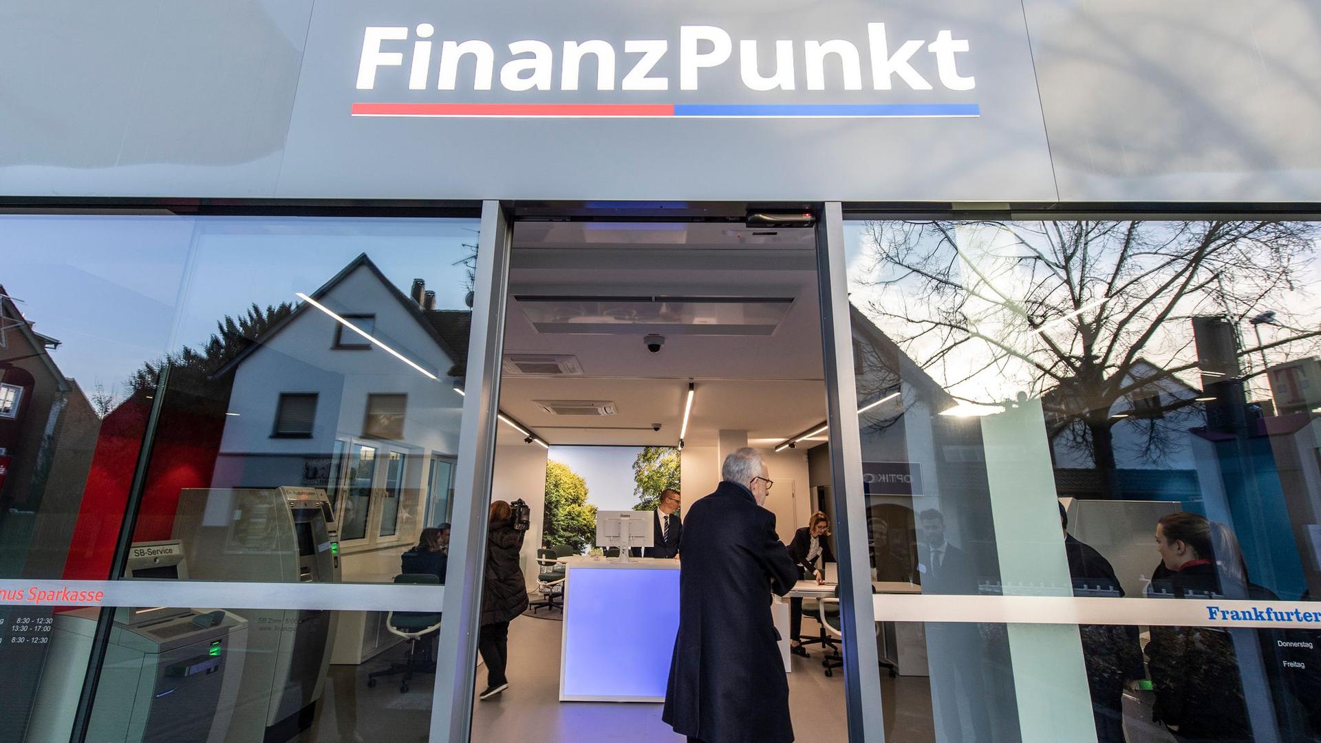 Besucher stehen zur Eröffnung vor dem „Finanzpunkt“. In der Bankfiliale kooperieren die Taunus Sparkasse und die Frankfurter Volksbank.