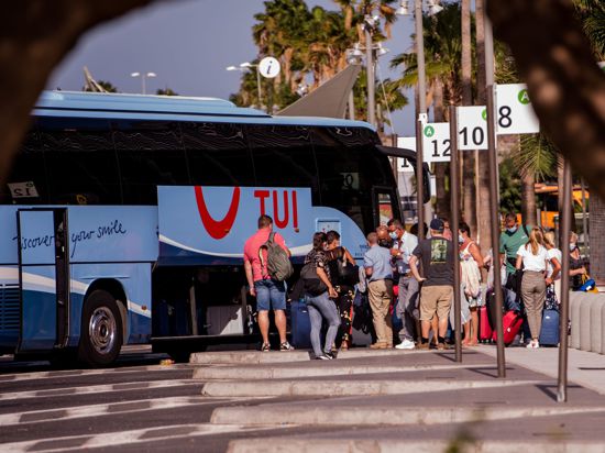 Touristen mit Mundschutz holen ihr Gepäck aus einem Bus des Tourismuskonzerns Tui nahe des Flughafens auf Tenerife.