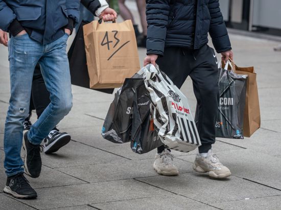 Junge Männer schleppen Einkaufstüten, während auf der Frankfurter Einkausmeile Zeil am Samstag des zweiten Adventswochendes reger Betrieb herrscht.