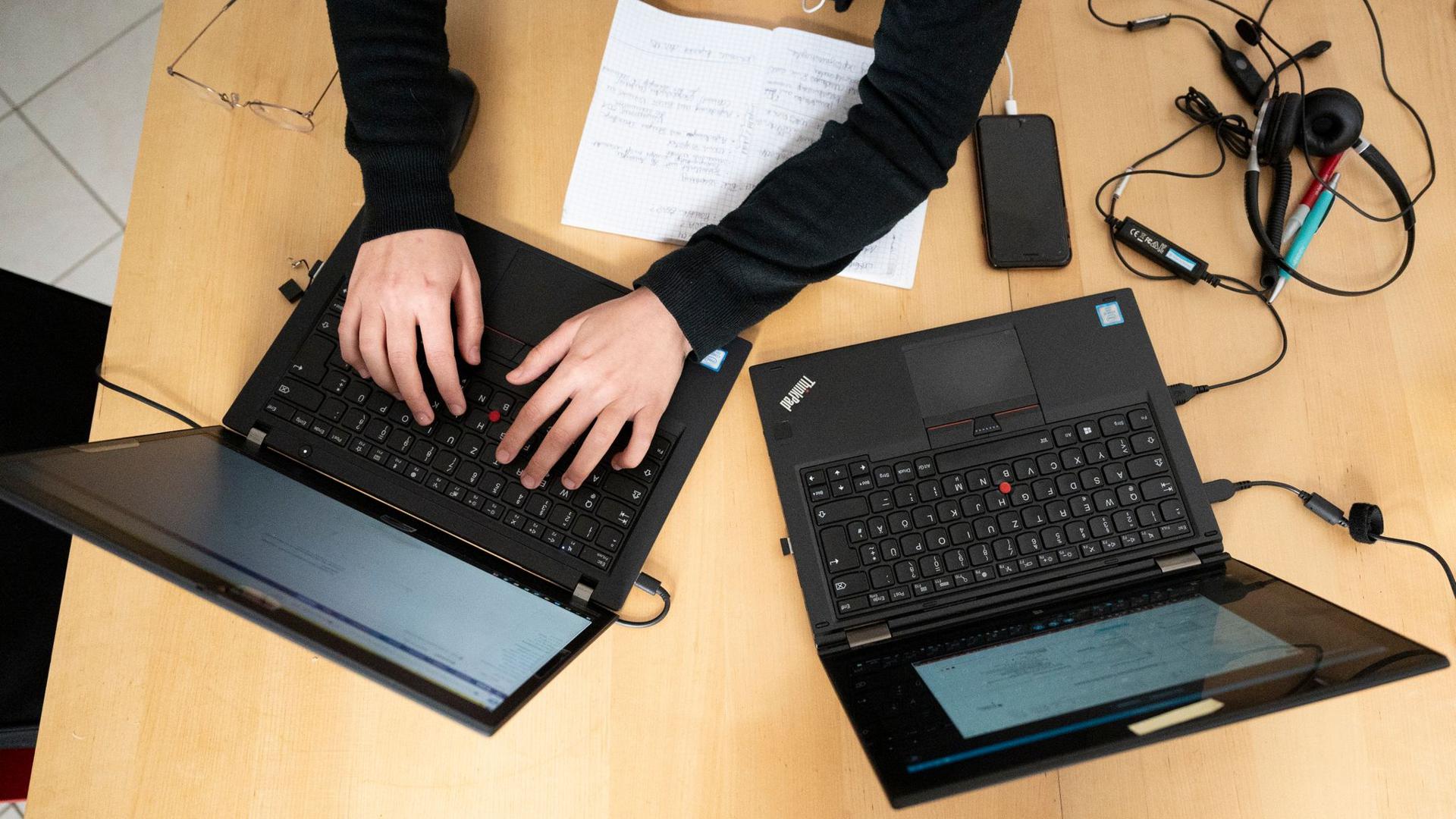 Eine Person nutzt zwei Laptops.