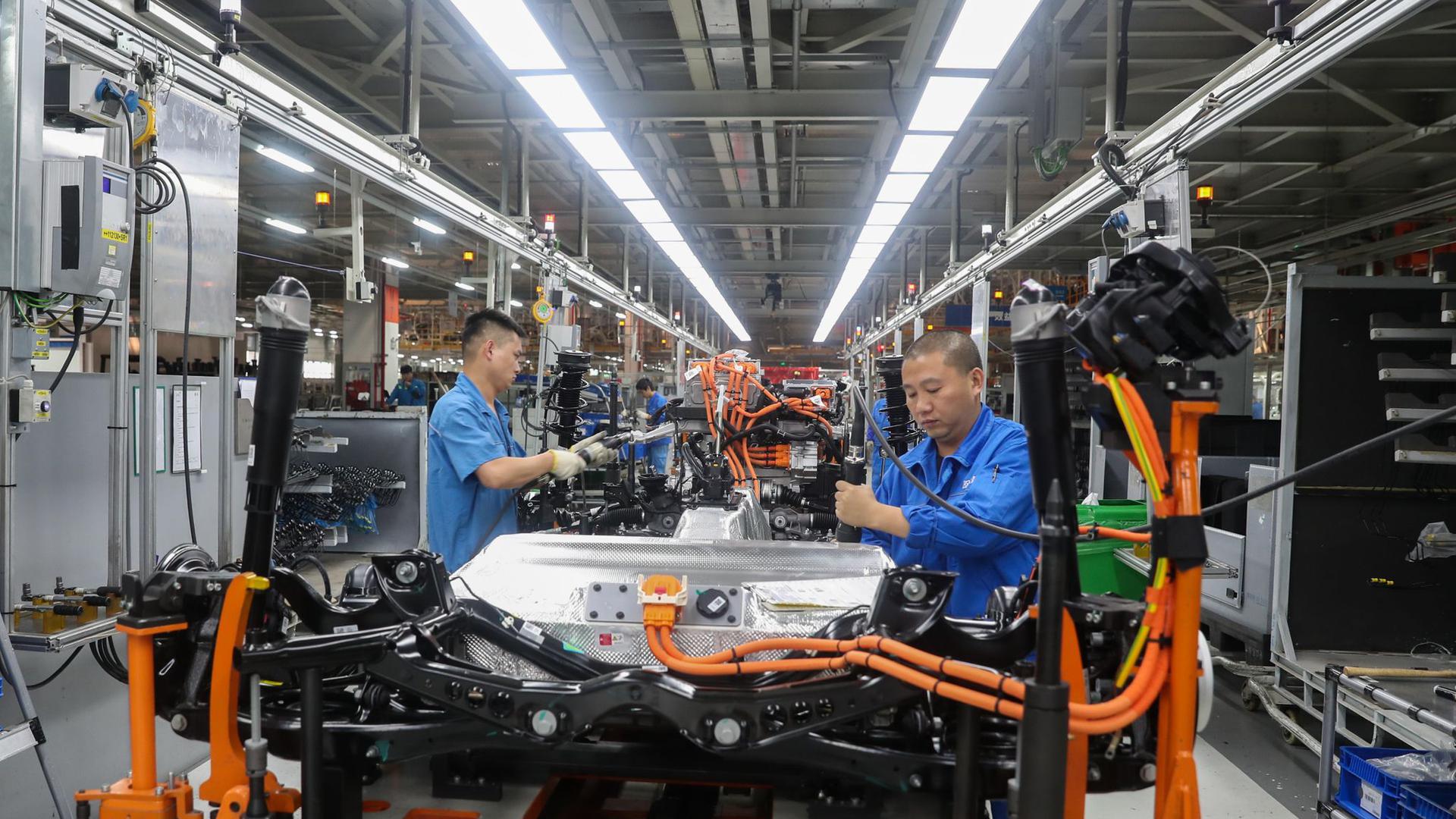 Fahrzeugbauer arbeiten in einer Werkshalle in Shanghai an einer Produktionslinie von SAIC Volkswagen.
