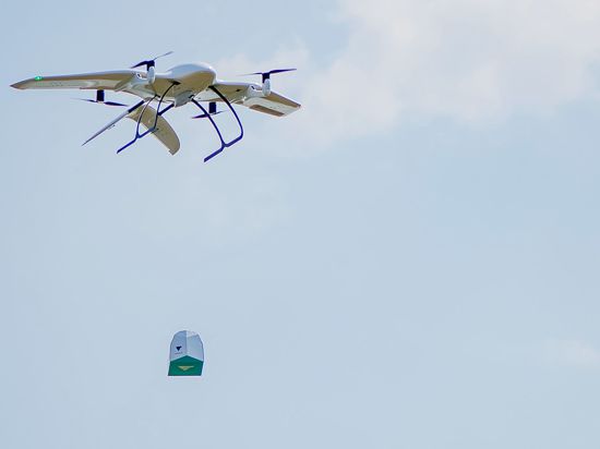 Eine Drohne des Start-Ups Wingcopter trägt ein Paket. Das mit Tragflächen ausgestattete Gerät kann senkrecht aufsteigen und dann auf der Strecke auch bei widrigen Wetterverhältnissen wie ein Propeller-Flugzeug fliegen.